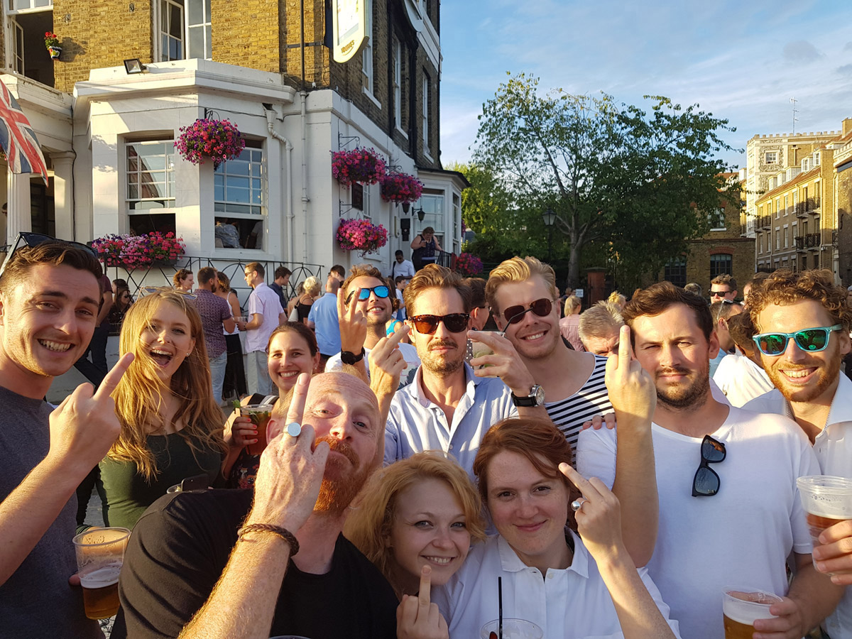 Group of people smiling and swearing at camera outside a pub