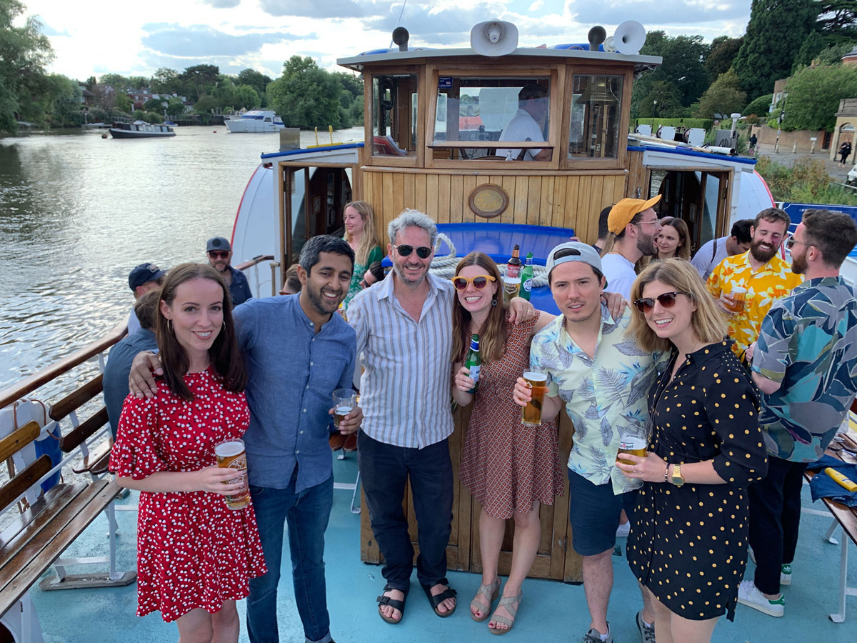 Group of smiling people with drinks on a boat, looking to camera